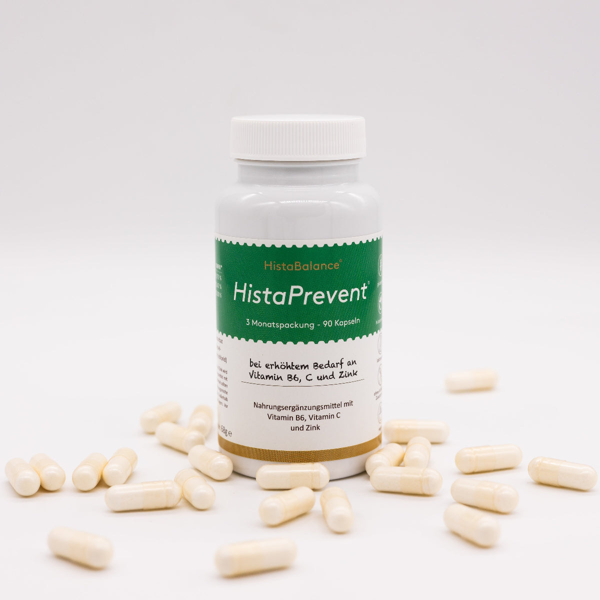 Dose „HistaPrevent“ mit grün-weißem Etikett steht im Zentrum, umgeben von verstreuten weißen Kapseln auf weißem Hintergrund. Text auf der Dose: „bei erhöhtem Bedarf an Vitamin B6, C und Zink“.