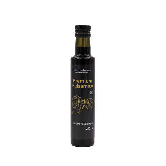 Eine schwarze, schmale Flasche mit schwarzem Deckel und der Aufschrift "Premium Balsamico Bio". Die Flasche wird als histaminarm und vegan bezeichnet. Unter der Aufschrift sind zwei Weinblätter abgebildet.