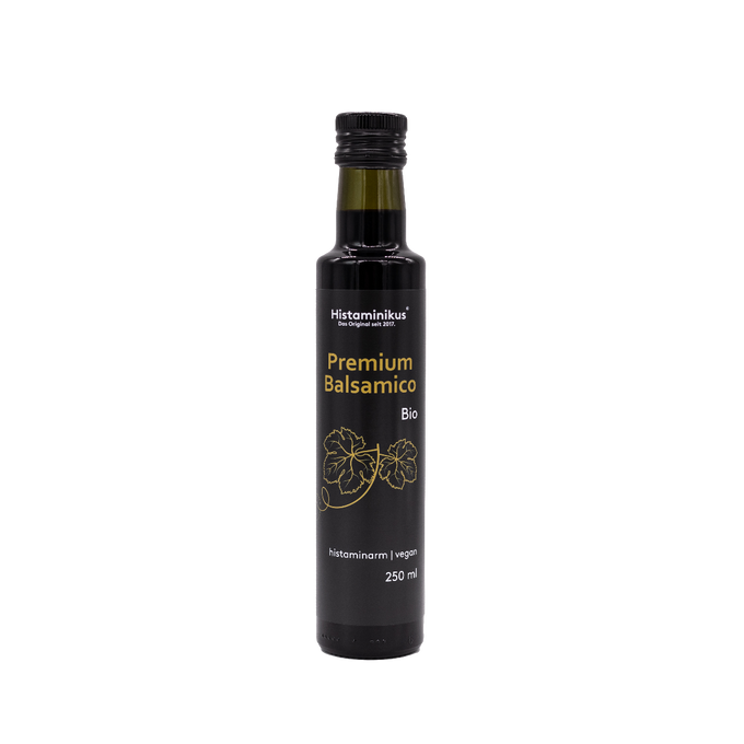 Eine schwarze, schmale Flasche mit schwarzem Deckel und der Aufschrift "Premium Balsamico Bio". Die Flasche wird als histaminarm und vegan bezeichnet. Unter der Aufschrift sind zwei Weinblätter abgebildet.