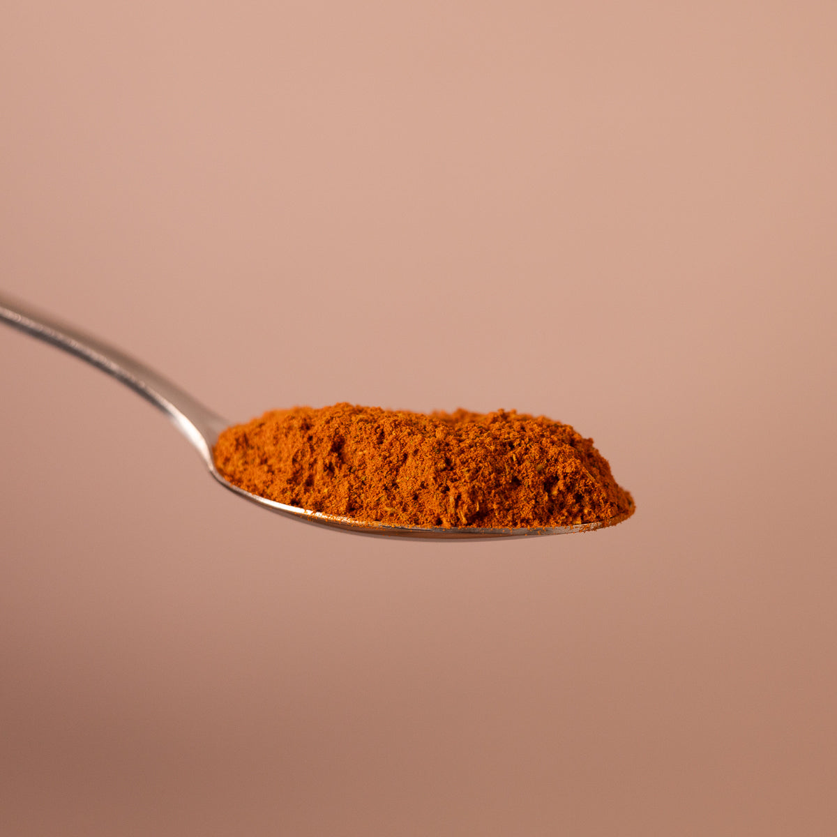 Esslöffel mit einer kleinen Menge Kartoffelwürze-Pulver. Das Pulver ist kräftig rot-orange.
