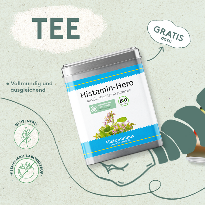 Grafik mit Dose „Histamin-Hero – ausgleichender Kräutertee“ auf hellem Hintergrund. Etikett in Weiß und Blau mit Kräuterillustration und Bio-Siegel. Links Text: „vollmundig und ausgleichend“ sowie Icons „glutenfrei“ und „histaminarm laborgeprüft“. Oben rechts Hinweis: „Gratis dazu“.