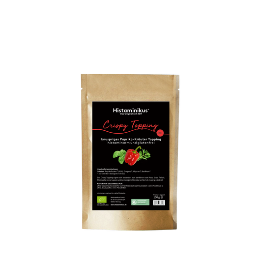 Braune Standbodenverpackung mit schwarzem Etikett. Produktname „Crispy Topping – knuspriges Paprika-Kräuter Topping“. Abbildung einer Paprika mit Kräutern, Hinweis: histaminarm, glutenfrei, Bio.