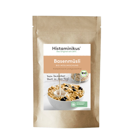 Braune Standbodenverpackung mit Etikett des Produkts „Basenmüsli“. Aufschrift „Histaminikus, das Original seit 2017“. Darunter Produktname „Basenmüsli – Bio-Müslimischung“. Text „histaminarm und glutenfrei“. Abgebildet ist eine weiße Schale mit Müsli, Milch wird hineingegossen. Im Müsli sind dunkle Beeren zu erkennen. Links daneben steht „Dein basischer Start in den Tag!“. Bio-Siegel und ein grünes Icon mit „Histaminarm & Glutenfrei laut Rezeptur“.
