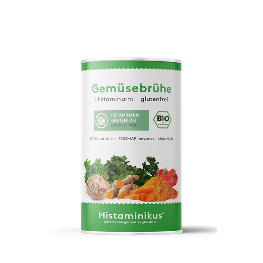 Weiße Dose mit grünem Deckelrand und grünem Etikett unten. Aufschrift „Gemüsebrühe – Histaminarm, glutenfrei“. Abgebildet sind verschiedene Gemüse und Gewürze wie Sellerie, Kurkuma, Karotten, Petersilie und Paprika. Daneben ein grünes „BIO“-Siegel.