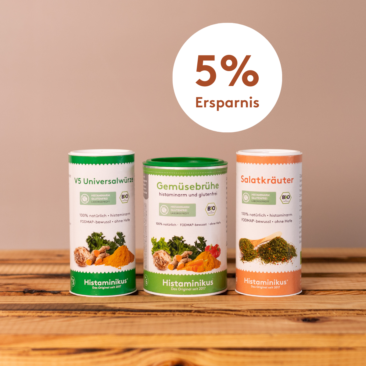 Drei Bio-Würzdosen von Histaminikus – V5 Universalwürze, Gemüsebrühe und Salatkräuter – nebeneinander auf einem Holztisch vor beigem Hintergrund, darüber ein Kreis mit dem Schriftzug „5 % Ersparnis"