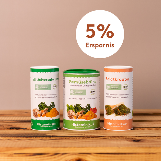 Drei Bio-Würzdosen von Histaminikus – V5 Universalwürze, Gemüsebrühe und Salatkräuter – nebeneinander auf einem Holztisch vor beigem Hintergrund, darüber ein Kreis mit dem Schriftzug „5 % Ersparnis"