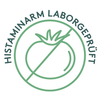 Grafik eines kreisförmigen Siegels mit einer stilisierten durchgestrichenen Tomate in der Mitte. Der umlaufende Schriftzug lautet „Histaminarm laborgeprüft“. Die Gestaltung ist in einem dezenten Grünton gehalten.