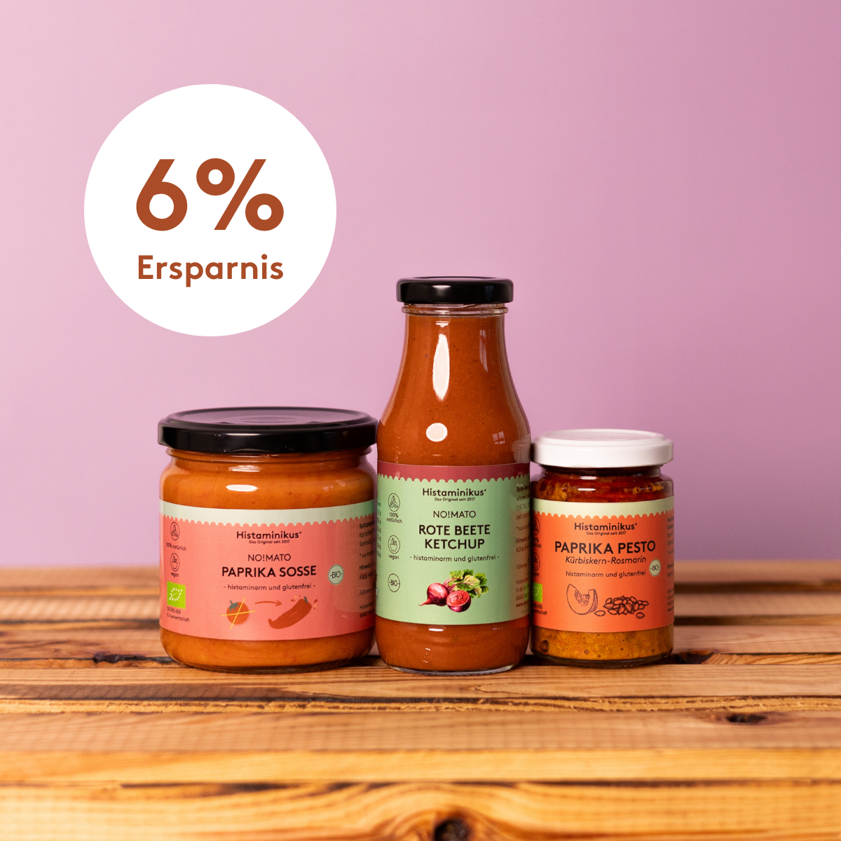 Drei histaminarme Produkte von Histaminikus – NO!MATO Paprikasoße, Rote-Bete-Ketchup und Paprika-Pesto – nebeneinander auf einem Holztisch vor violettem Hintergrund.
