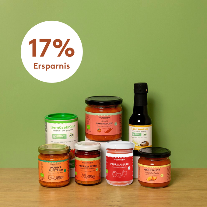 Acht histaminarme Produkte von Histaminikus – darunter Gemüsebrühe, Paprikasoße, Coco Aminos, Paprikamark, Paprika-Aufstrich, Paprika-Pesto und Grillsauce – auf hellem Holztisch vor grünem Hintergrund mit dem Hinweis „17 % Ersparnis“.