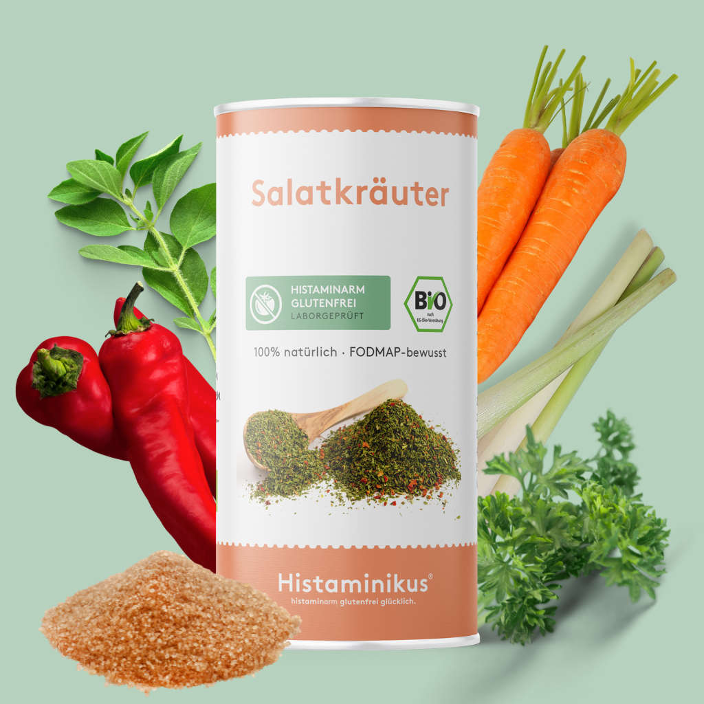 Produktfoto der „Salatkräuter“ von Histaminikus mit prominent platzierter Dose im Zentrum. Darum arrangiert sind ausgewählte Zutaten wie Karotten, Zitronengras, Paprika, Oregano, Petersilie und Rohrohrzucker. Die Etikettengestaltung hebt Merkmale wie „histaminarm“, „glutenfrei“, „FODMAP-bewusst“ und „Bio“ hervor. Die Darstellung unterstreicht den natürlichen und allergenarmen Charakter der Mischung.