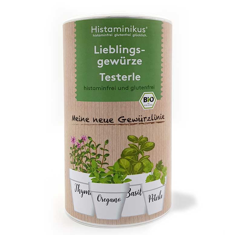 Dose mit Holzoptik-Etikett und grünem Aufdruck „Lieblingsgewürze Testerle – histaminfrei und glutenfrei“. Unten vier gezeichnete Kräutertöpfe beschriftet mit Thymian, Oregano, Basilikum und Petersilie. Darüber Text „Meine neue Gewürzlinie“ und ein Bio-Siegel.