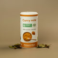 Dose „Curry mild“ mit orange-weißem Etikett auf beigem Hintergrund. Darauf Bio- und histaminarm-Siegel, Text: 100 % natürlich, ohne Hefe. Umgeben von Lorbeerblättern und Gewürznelken.