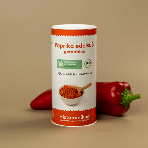 Dose „Paprika edelsüß gemahlen“ von Histaminikus in Nahaufnahme vor beige-braunem Hintergrund, im Vordergrund eine frische rote Paprika.
Auf der Dose: grüne Label „histaminarm, glutenfrei, laborgeprüft“ sowie BIO-Siegel
Darunter ein Schälchen mit Paprikapulver und Holzlöffel
Text: „100 % natürlich • histaminarm“
Unten: Marke Histaminikus – histaminfrei glutenfrei glücklich