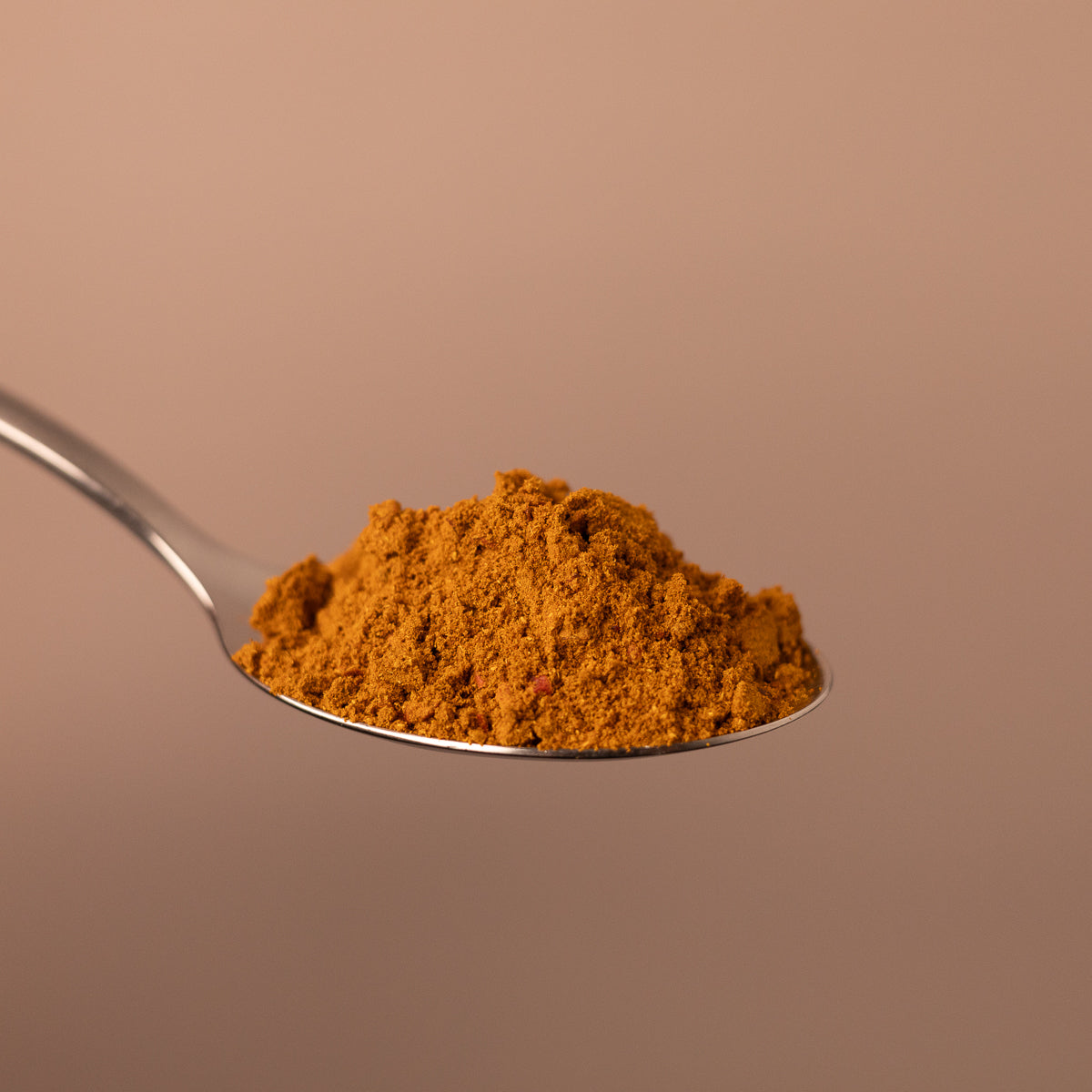 Fein gemahlenes asiatisches Gewürzpulver auf einem Löffel vor schlichtem Hintergrund.