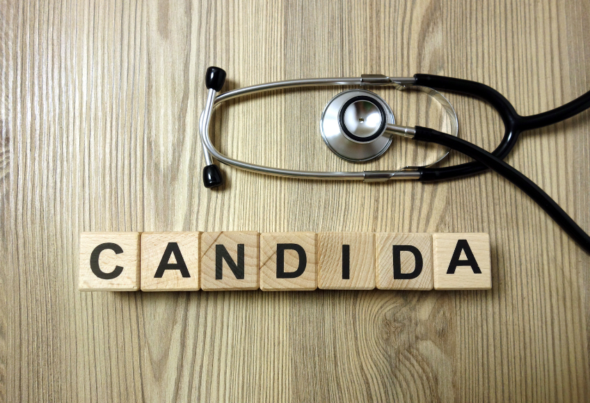 Stethoskop auf Holzuntergrund, oberhalb von sieben Holzklötzchen, die nebeneinander das Wort „CANDIDA“ bilden.
