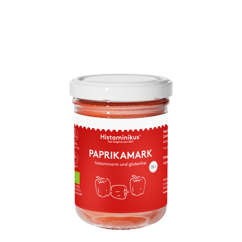Kleines Glas mit weißem Deckel und rotem Etikett. Auf dem Etikett steht PAPRIKAMARK und darunter sind drei Paprika gezeichnet. Der Inhalt des Glases ist hellrot-orange. Außerdem wird der Inhalt laut Etikett als histaminarm und glutenfrei bezeichnet.