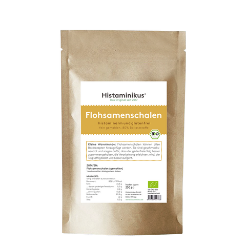 Braune Papierverpackung mit weißem Etikett. Produktname „Flohsamenschalen“ in großer gelber Schrift, darunter Beschreibung „histaminarm und glutenfrei, fein gemahlen, 80 % Ballaststoffe“. Mit Bio-Siegel und Infotext zur Verwendung.