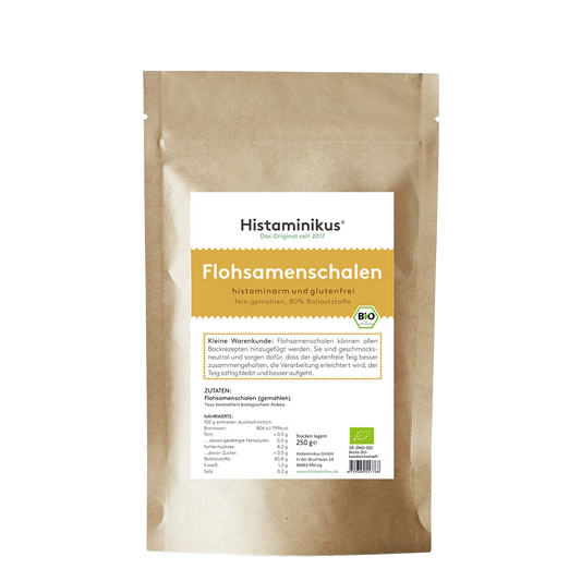 Braune Papierverpackung mit weißem Etikett. Produktname „Flohsamenschalen“ in großer gelber Schrift, darunter Beschreibung „histaminarm und glutenfrei, fein gemahlen, 80 % Ballaststoffe“. Mit Bio-Siegel und Infotext zur Verwendung.