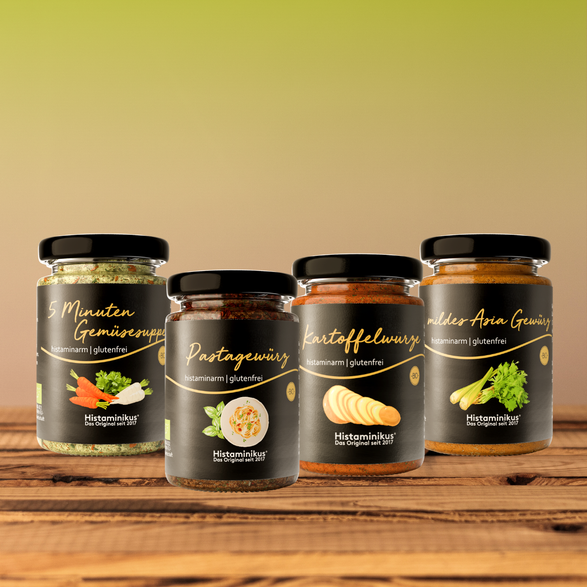 Vier histaminarme, glutenfreie Gewürze von Histaminikus in Gläsern: 5 Minuten Gemüsesuppe, Pastagewürz, Kartoffelwürze und mildes Asia Gewürz, arrangiert auf einem Holztisch vor warmem Farbverlauf-Hintergrund.