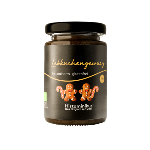 kleines Glas mit schwarzem Deckel und schwarzem Etikett mit der Schrift Lebkuchengewürz sowie zwei lustigen Lebkuchenkeksen mit Gesichtern und Zuckerstangen