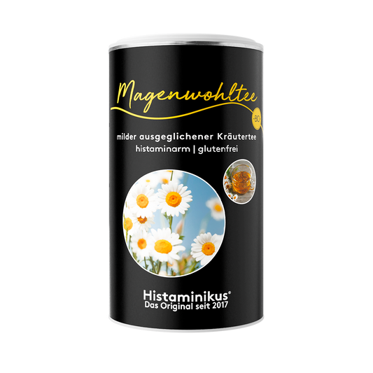 Schwarze Dose Histaminikus Magenwohltee mit gelber Schrift, Aufschrift „milder ausgeglichener Kräutertee, histaminarm, glutenfrei“, unten Foto von Kamillenblüten und Teeglas.