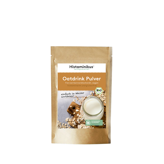 Braune Standbeutelverpackung von Histaminikus Oatdrink Pulver mit Glas Hafermilch und Bio- sowie Histaminfrei-Siegel auf dem Etikett.