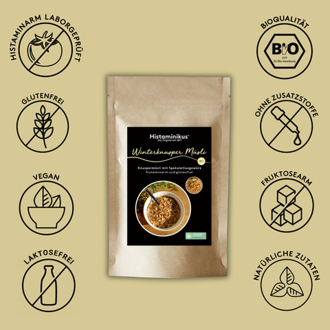 Produktabbildung von Histaminikus Winterknusper Müsli in einer braunen Standbodenverpackung mit schwarzem Etikett und Schale Müsli auf der Vorderseite. Rund um die Verpackung sind Siegel dargestellt: histaminarm laborgeprüft, Bioqualität, glutenfrei,
