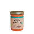 Glas mit orangem Inhalt und goldenem Deckel. Etikett mit der Aufschrift: Paprikaaufstrich. Der Inhalt wird als histaminarm und glutenfrei bezeichnet. Außerdem sind auf dem Etikett zwei Paprika und Kürbiskerne zu sehen. Das Bio-Siegel ist rechts in einem kräftigen Türkis aufgedruckt.