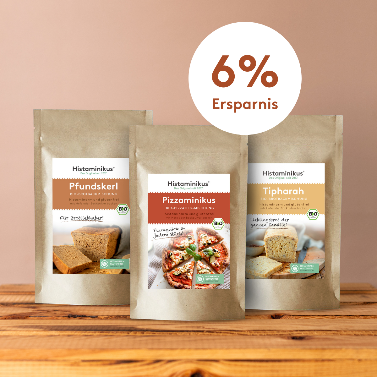Drei Bio-Backmischungen von Histaminikus – Pfundskerl, Pizzaminikus und Tipharah – nebeneinander auf einem Holztisch vor beigem Hintergrund, darüber ein Kreis mit dem Hinweis „6 % Ersparnis“.