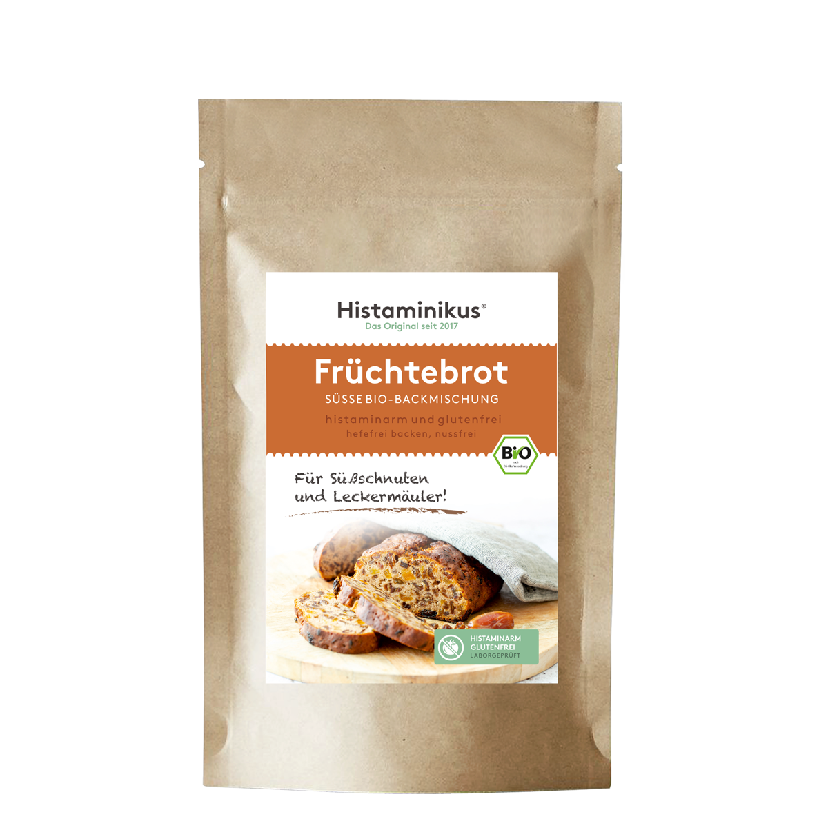 Braune Papierverpackung mit weißem Etikett. Produktname „Früchtebrot“ in orangener Schrift, darunter „süße Bio-Backmischung, histaminarm und glutenfrei“. Foto eines angeschnittenen Früchtebrots auf Holzbrett, mit Bio-Siegel und Slogan „Für Süßschnuten und Leckermäuler!“
