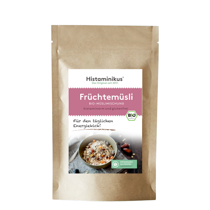 Braune Papierverpackung mit weißem Etikett. Produktname „Früchtemüsli“ in rosa Schrift, darunter „Bio-Müslimischung, histaminarm und glutenfrei“. Foto einer Müslischale mit Löffel und Trockenfrüchten.