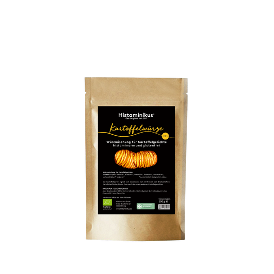Standbeutel mit schwarzem Etikett. Oben steht „Histaminikus“, darunter in gelber Handschrift „Kartoffelwürze“. Beschriftung: „Würzmischung für Kartoffelgerichte – histaminarm und glutenfrei“. Abgebildet sind zwei gebackene Hasselback-Kartoffeln. Unten diverse Angaben zur Verwendung, Zutaten, Bio-Siegeln und Verpackungsinformationen.
