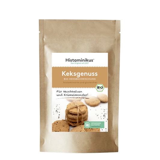 Braune Papierverpackung mit weißem Etikett. Aufschrift „Histaminikus – Keksgenuss – Bio-Keksbackmischung“, darunter „histaminarm und glutenfrei“. In der Mitte ein Foto mit mehreren Keksen, ein paar lose, andere zu einem Stapel gebunden. Daneben der Text „Für Naschkatzen und Krümelmonster!“, unten ein grünes Label mit dem Hinweis „histaminarm, glutenfrei, laborgeprüft“.