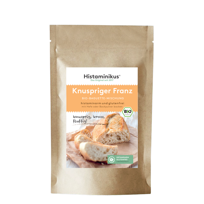 Produktabbildung der braunen Kraftpapierverpackung mit Etikett „Knuspriger Franz – Bio-Baguette-Mischung“. Untertitel: „histaminarm und glutenfrei – mit Hefe oder Backpulver backen“. Im unteren Bereich ein Foto von frisch gebackenem Baguette auf einem Holzbrett, mit dem handschriftlichen Zusatz „knusprig, kross, fluffig!“. Daneben grüne Siegel für „histaminarm glutenfrei“ und Bio-Qualität.