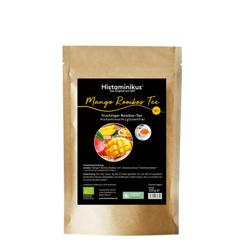 Standbeutel aus braunem Kraftpapier mit schwarzem Etikett von Histaminikus. Auf dem Etikett steht „Mango Rooibos Tee“ sowie „fruchtiger Rooibos-Tee, histaminarm | glutenfrei“. Abgebildet sind eine aufgeschnittene Mango und eine Tasse Tee, daneben ein gelbes BIO-Siegel. Im unteren Bereich stehen Zutaten, Zubereitung, Bio-Kennzeichnung, ein grünes Prüfsiegel sowie die Füllmenge von 100 g.