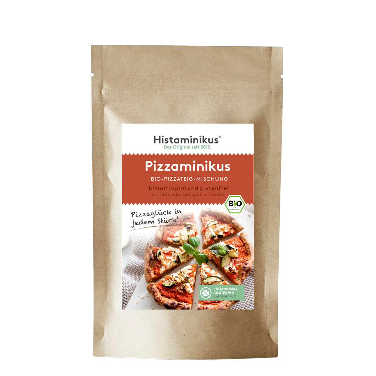 Brauner Standbodenbeutel mit zentralem, weiß-rot gestaltetem Etikett von Histaminikus; Produktname „Pizzaminikus – Bio-Pizzateig-Mischung“. Unterzeile „histaminarm und glutenfrei, mit Hefe oder Backpulver backen“. Rechts am Etikett ein grünes BIO-Siegel. Darunter Produktfoto: runde Pizza, in Stücke geschnitten, mit weißem Belag und Basilikum; daneben handschriftlicher Spruch „Pizzaglück in jedem Stück!“. Unten rechts ein grünes Siegel „Histaminarm – Glutenfrei – Laborgeprüft“.