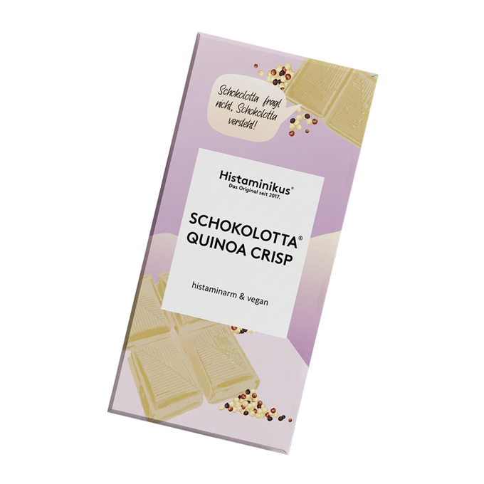Schräg dargestellte Verpackung der veganen, histaminarmen Schokolade „Schokolotta Quinoa Crisp“ von Histaminikus mit weißem Etikett, handschriftlicher Sprechblase, weißen Schokoladenstücken, Quinoa-Crisps.