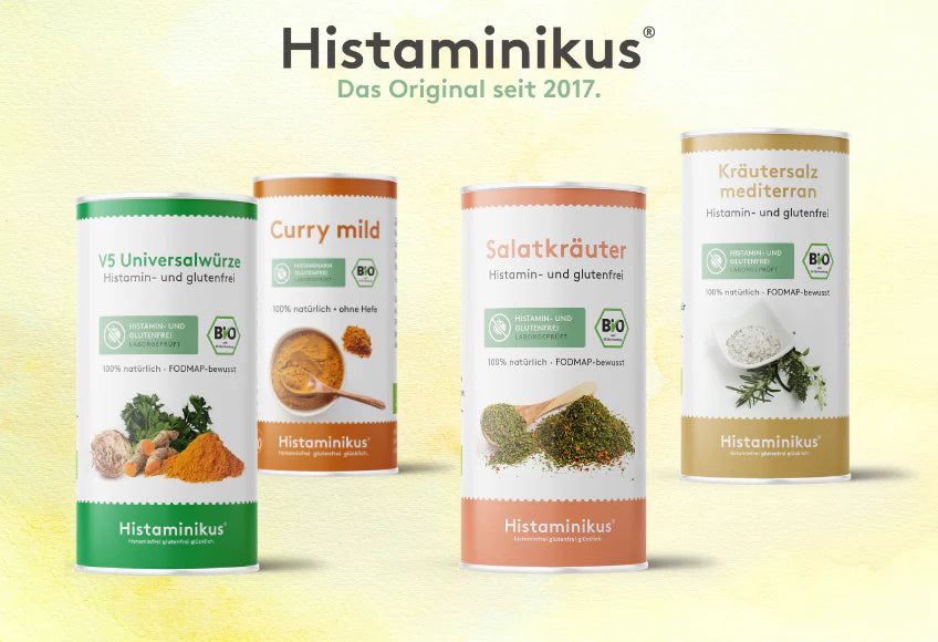 Vier Dosen Histaminikus-Gewürze auf hellem Untergrund. Von links nach rechts: V5 Universalwürze, Curry mild, Salatkräuter, Kräutersalz mediterran. Über den Dosen der Schriftzug „Histaminikus – Das Original seit 2017.“ Alle Produkte tragen Bio- und Laborgeprüft-Siegel.