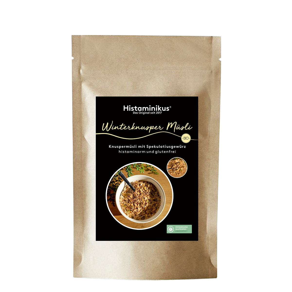 Stehende Papierverpackung „Winterknusper Müsli“ von Histaminikus  mit schwarzem Etikett, hellgelber Schrift, Abbildung einer Müslischale mit Knuspermüsli sowie Bio-Siegel und Produkthinweisen.